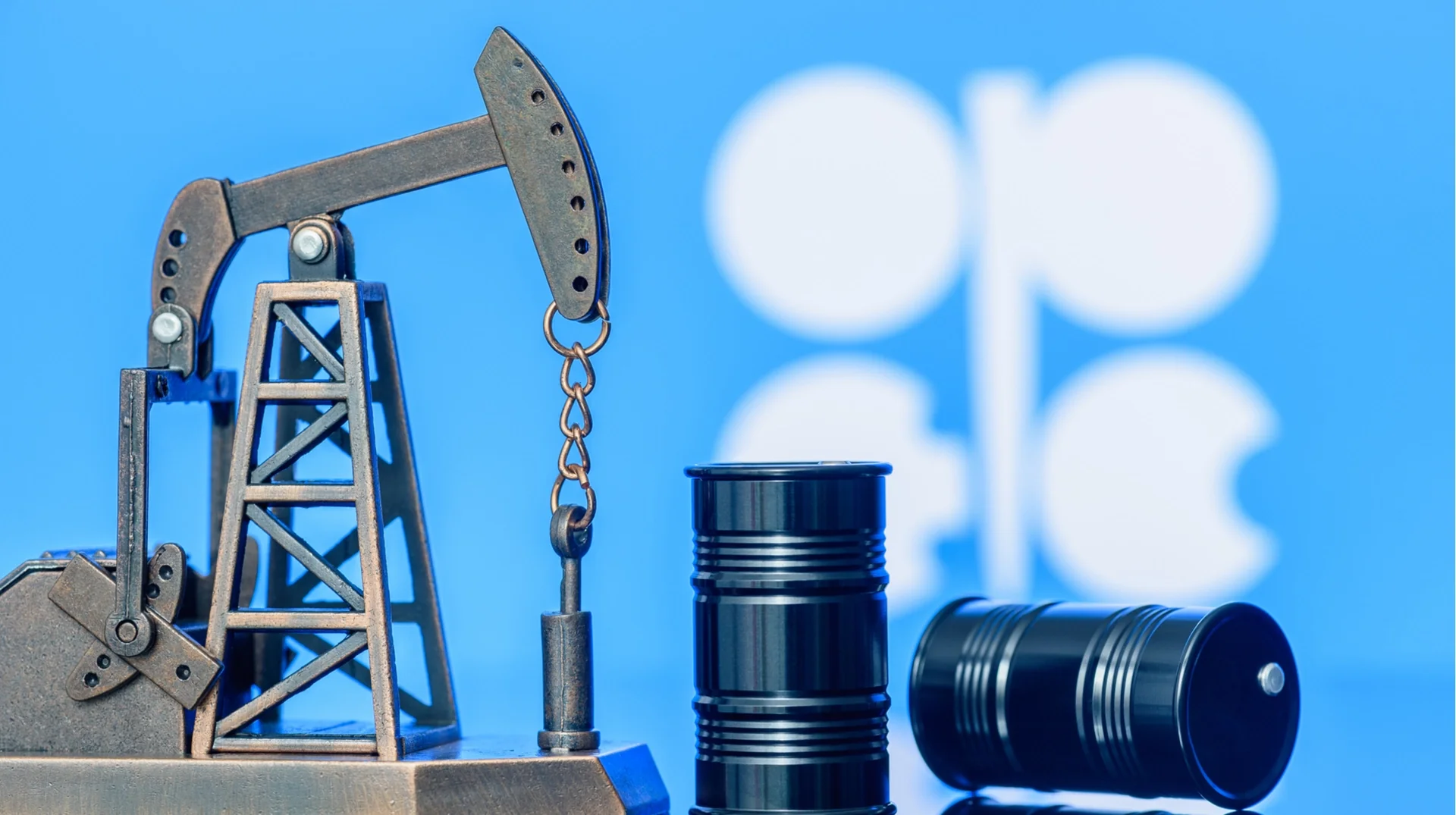 Модель нафтовидобувного насоса та бочки на тлі логотипу ОПЕК+